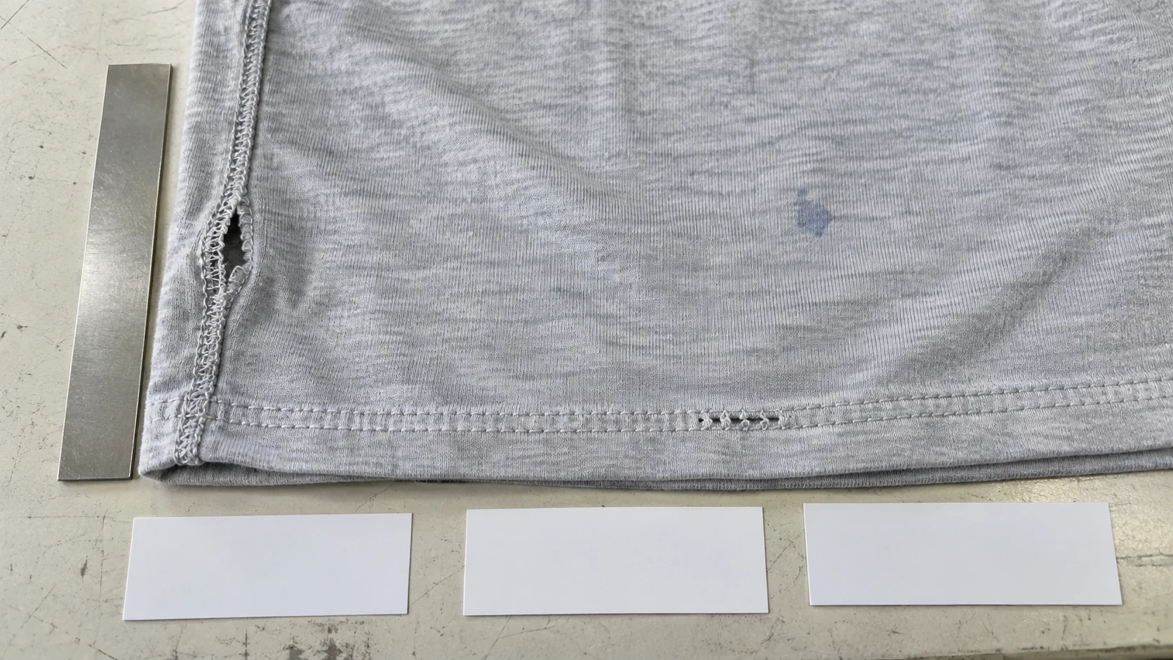 Garment inspection table with an open seam, skipped stitches and a small fabric mark